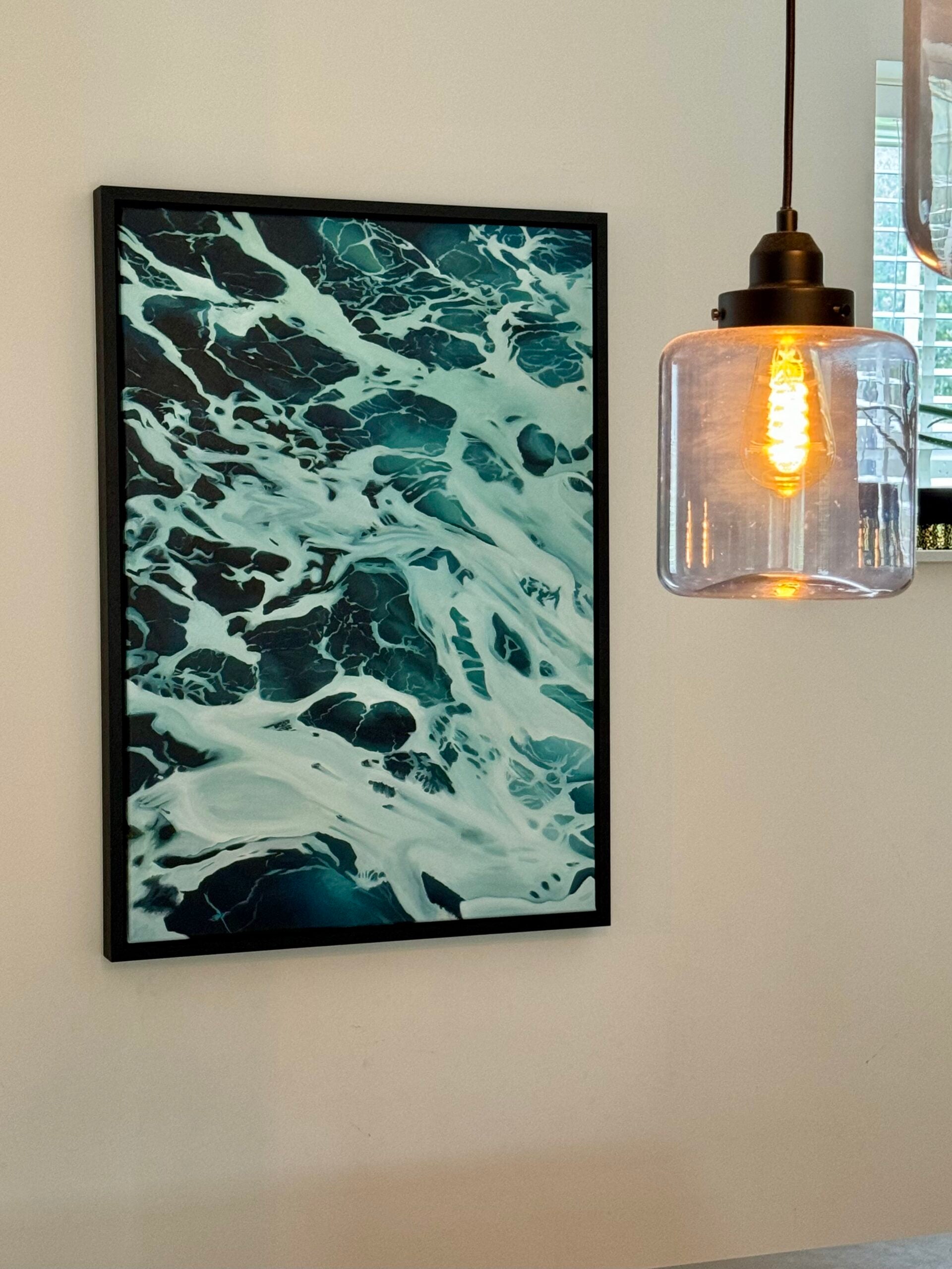 Framed abstract artwork on a wall with a pendant light fixture.